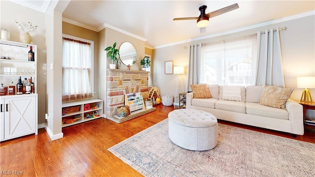 living room featuring a ceiling fan, wood finished floors, baseboards, and ornamental molding