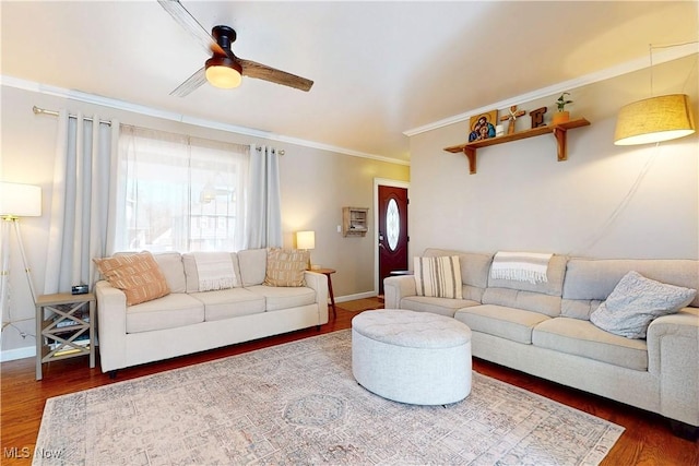 living room featuring wood finished floors, crown molding, a healthy amount of sunlight, and baseboards