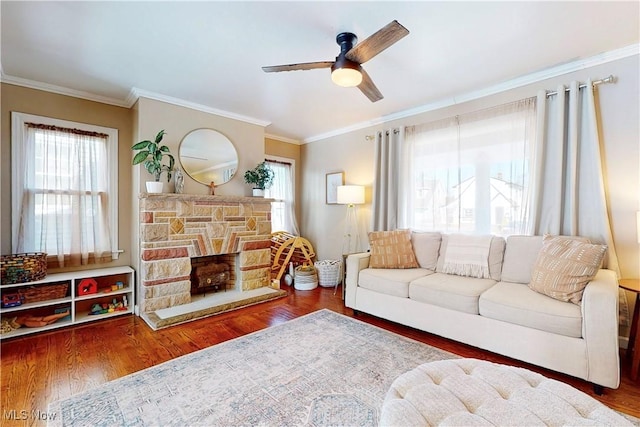 living area featuring a wealth of natural light, a fireplace, wood finished floors, and crown molding