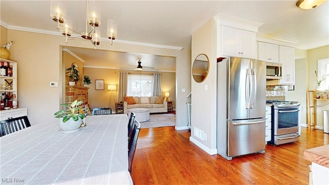 dining area with visible vents, ornamental molding, light wood-style floors, baseboards, and ceiling fan