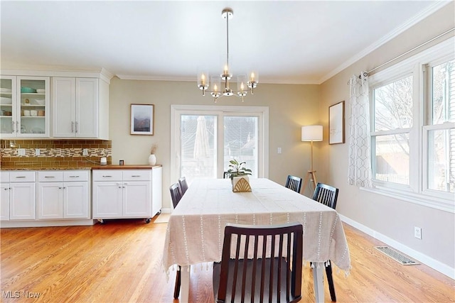 dining space with a wealth of natural light, visible vents, a notable chandelier, and light wood-style flooring