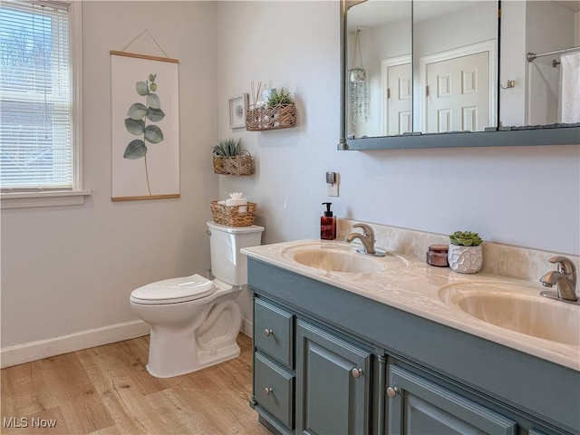 full bathroom with double vanity, toilet, wood finished floors, and a sink