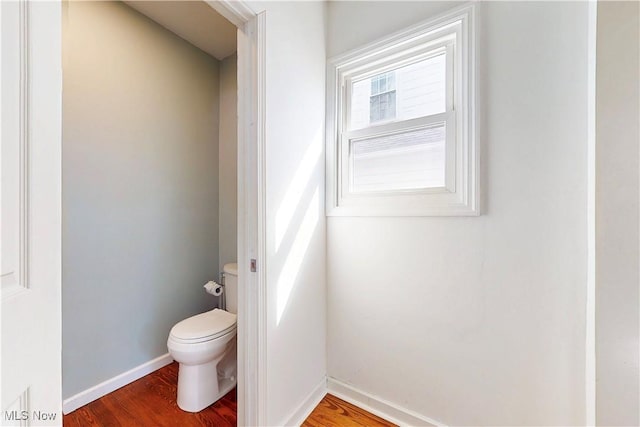 bathroom with toilet, wood finished floors, and baseboards