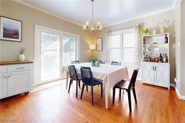 dining area featuring an inviting chandelier, light wood-style floors, baseboards, and ornamental molding