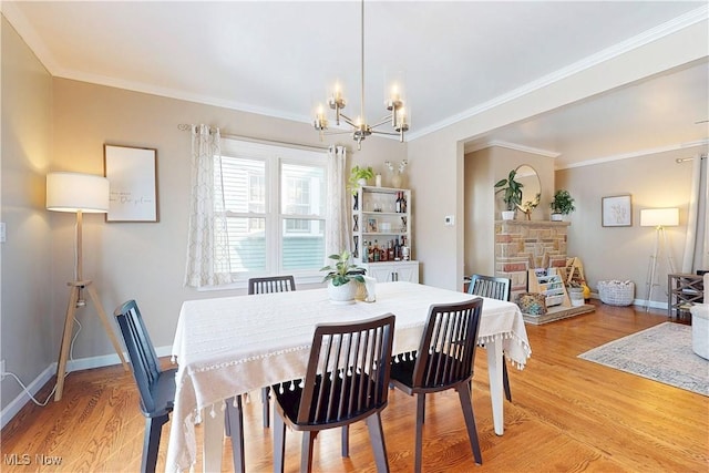 dining room with light wood-style flooring, baseboards, a chandelier, and ornamental molding