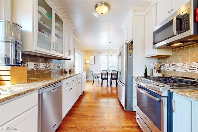 kitchen with light wood-type flooring, appliances with stainless steel finishes, white cabinets, and crown molding