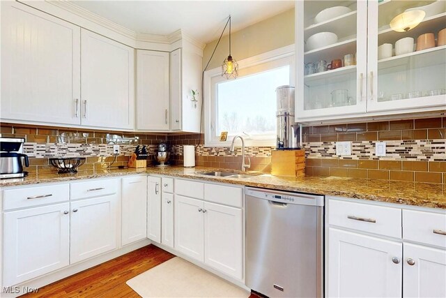 kitchen featuring light wood-type flooring, a sink, tasteful backsplash, stainless steel dishwasher, and white cabinetry