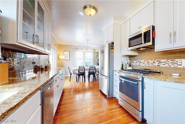 kitchen with decorative backsplash, white cabinetry, stainless steel appliances, and light wood-style floors