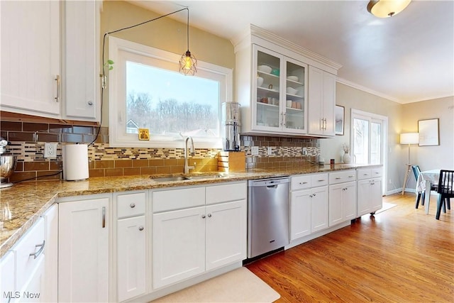 kitchen featuring white cabinetry, a sink, decorative backsplash, stainless steel dishwasher, and light wood-type flooring