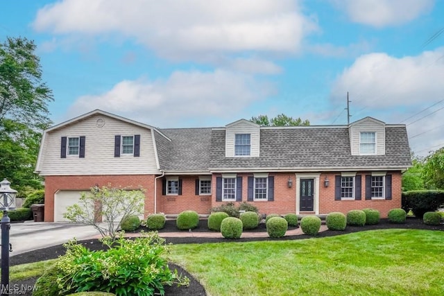 view of front of home featuring brick siding, a gambrel roof, driveway, and a front yard