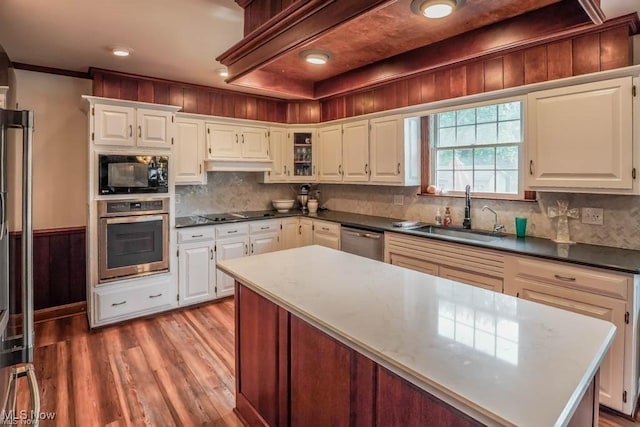 kitchen featuring black appliances, light wood-style flooring, a sink, white cabinetry, and decorative backsplash