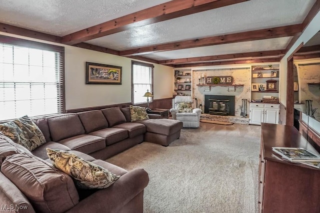 living room featuring a wainscoted wall, beamed ceiling, built in features, a textured ceiling, and carpet floors