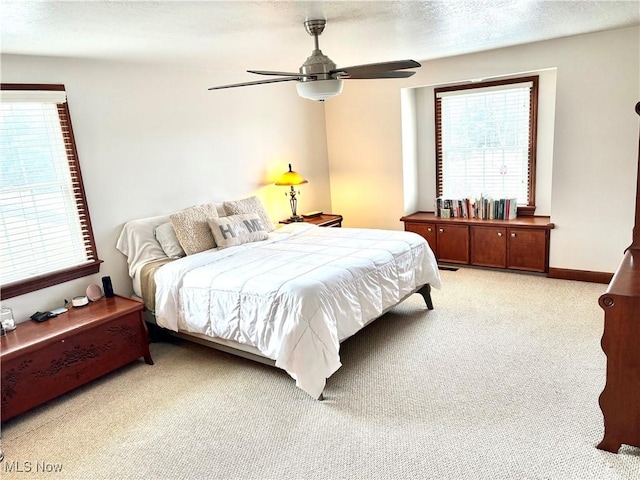 bedroom featuring a ceiling fan, light colored carpet, baseboards, and a textured ceiling