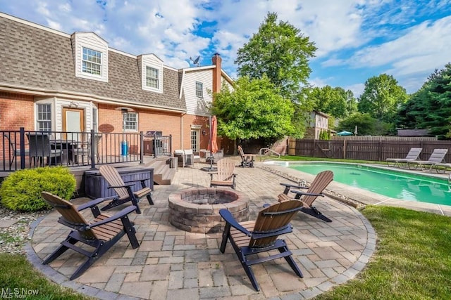 view of pool with a fire pit, a patio, and fence