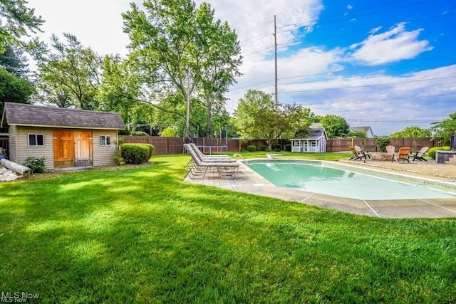 view of pool with a yard, a fire pit, an outbuilding, and a fenced backyard