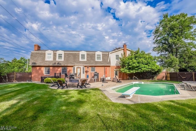 rear view of house with brick siding, an outdoor fire pit, a fenced backyard, a yard, and a patio area