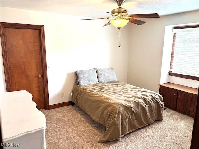 bedroom with a ceiling fan, baseboards, and light carpet