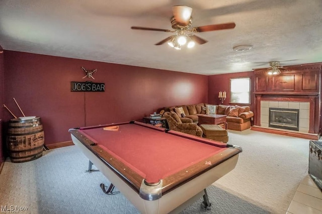 playroom featuring ceiling fan, pool table, a textured ceiling, a tiled fireplace, and carpet flooring