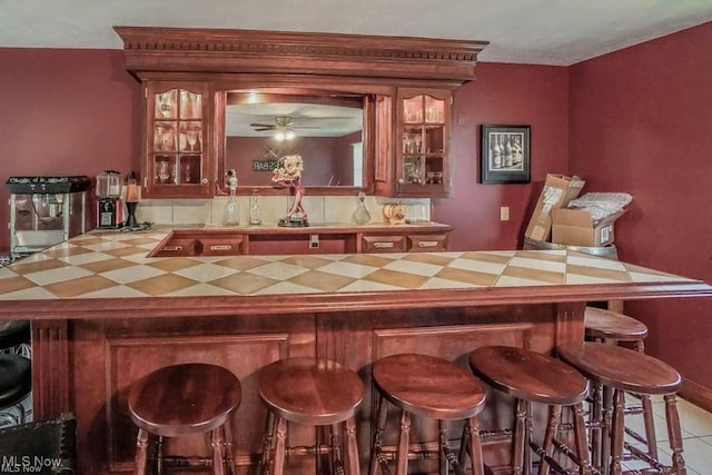 bar featuring tile patterned floors, indoor wet bar, and ceiling fan