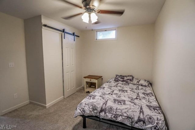 bedroom with light carpet, ceiling fan, baseboards, and a barn door