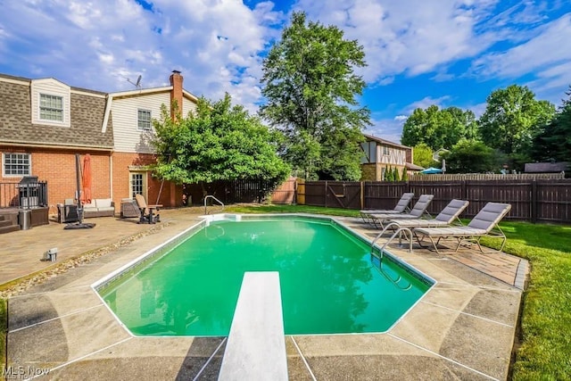 view of pool featuring a diving board, a fenced in pool, a fenced backyard, and a patio area