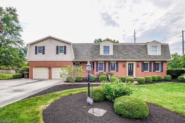 colonial inspired home with driveway, brick siding, a gambrel roof, and a shingled roof