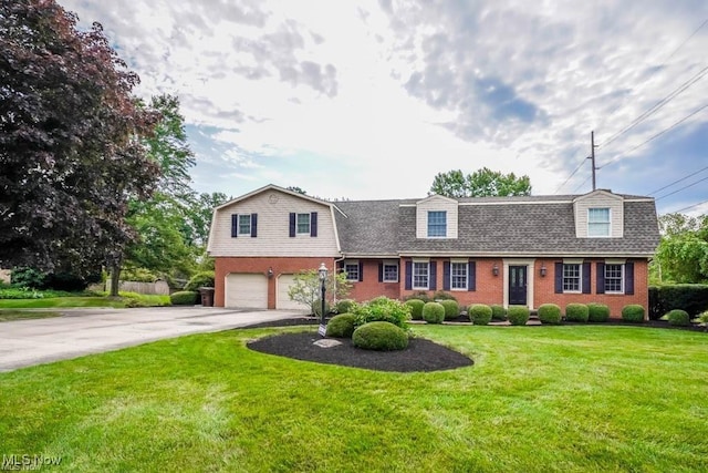 colonial inspired home with an attached garage, a gambrel roof, concrete driveway, a front lawn, and brick siding