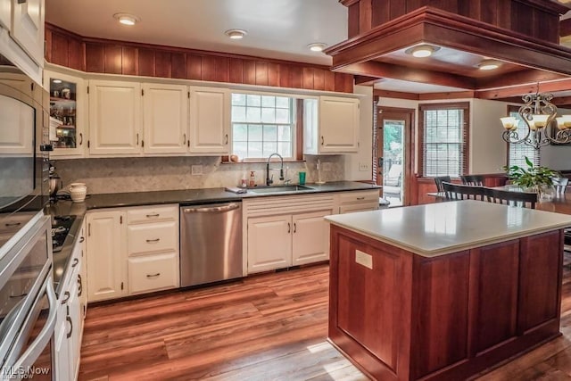 kitchen with wood finished floors, plenty of natural light, stainless steel appliances, and a sink