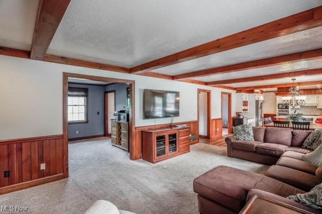 living area featuring beamed ceiling, wainscoting, and a textured ceiling