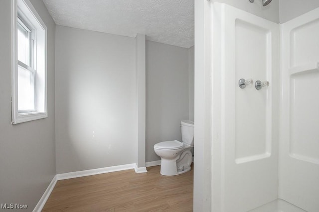 full bathroom featuring baseboards, toilet, wood finished floors, and a textured ceiling