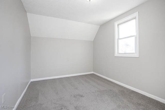 bonus room featuring baseboards, a textured ceiling, carpet flooring, and vaulted ceiling