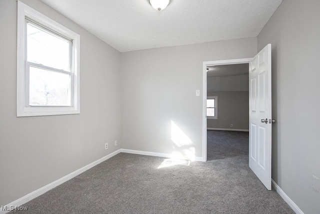 spare room with carpet flooring, baseboards, and a textured ceiling