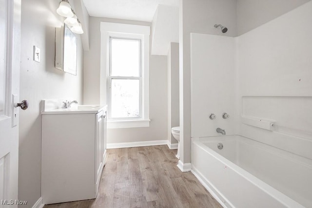 full bathroom featuring vanity, wood finished floors, baseboards, shower / tub combination, and toilet