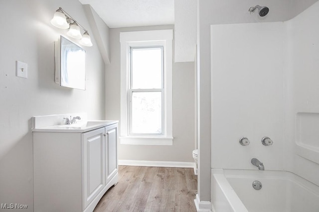 full bathroom with baseboards, toilet, shower / tub combination, wood finished floors, and vanity