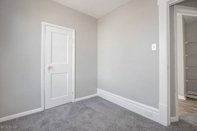 carpeted empty room with baseboards and a textured ceiling