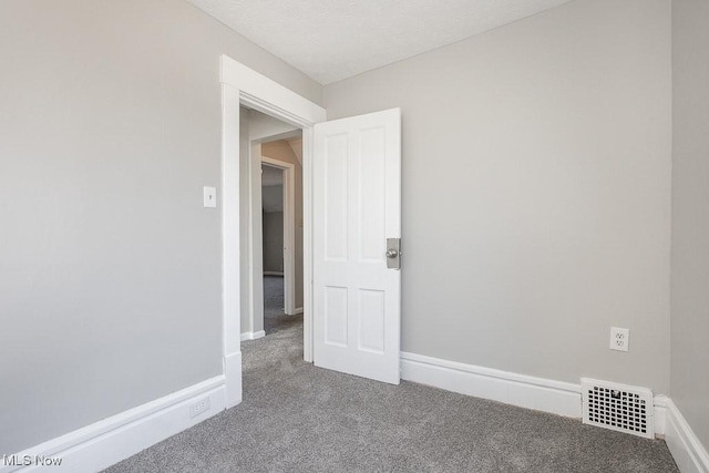 carpeted empty room featuring visible vents and baseboards