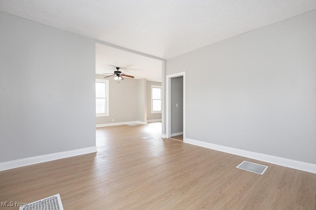 spare room with visible vents, ceiling fan, light wood-type flooring, and baseboards