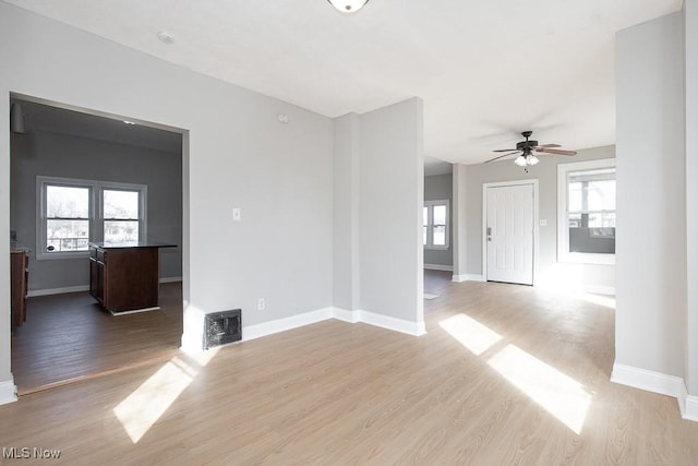 spare room featuring a wealth of natural light, visible vents, baseboards, and light wood-style floors