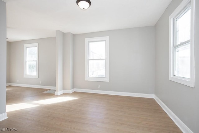 spare room with baseboards and light wood-style flooring