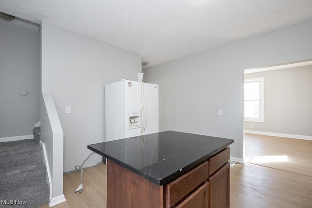 kitchen featuring baseboards, a kitchen island, a textured ceiling, and light wood finished floors