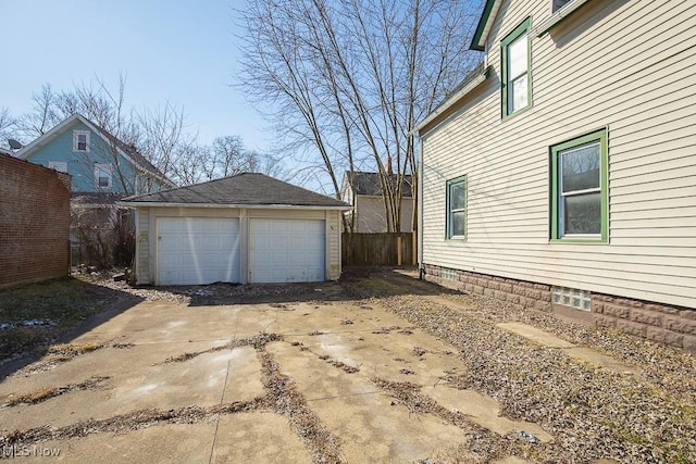 exterior space featuring a detached garage, an outbuilding, and fence