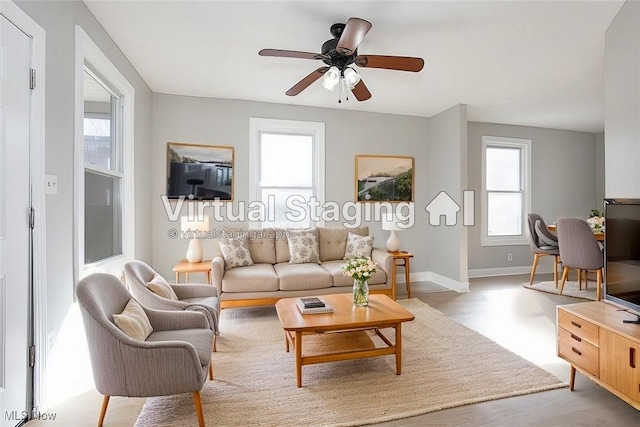 living room featuring light wood finished floors, a ceiling fan, and baseboards