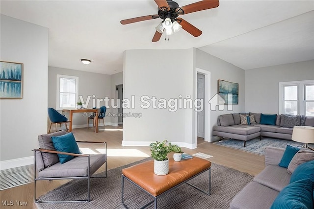 living room featuring a ceiling fan, baseboards, and light wood-type flooring