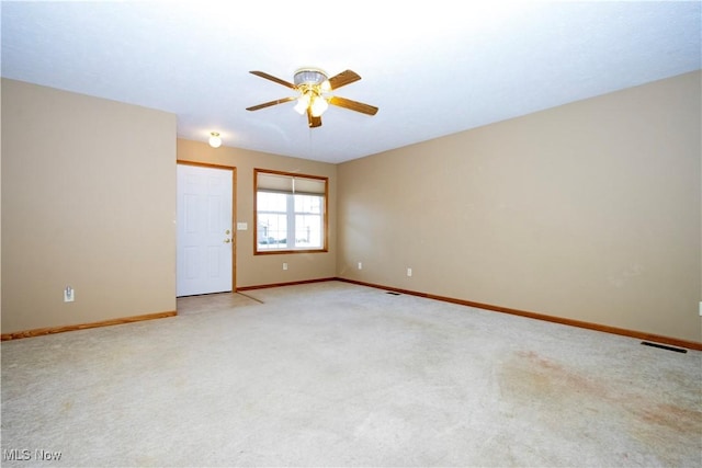 empty room with visible vents, baseboards, light colored carpet, and a ceiling fan