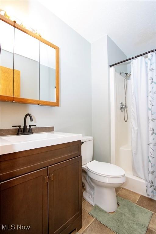 bathroom featuring tile patterned floors, curtained shower, toilet, and vanity