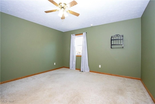 spare room featuring baseboards, light carpet, and ceiling fan