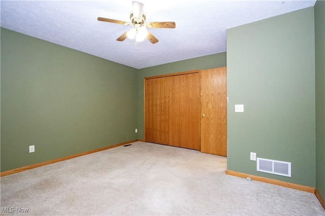 unfurnished bedroom with a closet, visible vents, light colored carpet, and baseboards