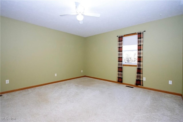 carpeted empty room with visible vents, a ceiling fan, and baseboards