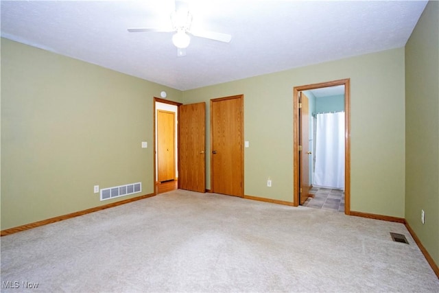 unfurnished bedroom featuring visible vents, baseboards, light carpet, and connected bathroom