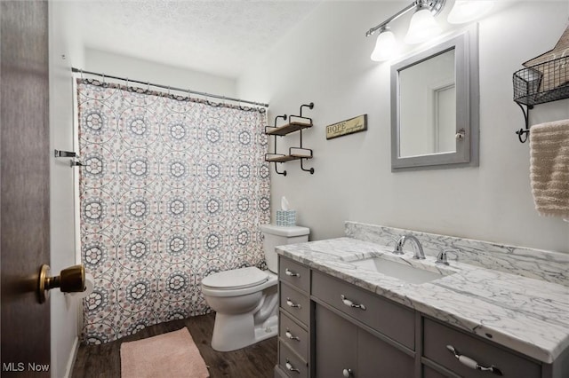 bathroom featuring toilet, curtained shower, a textured ceiling, wood finished floors, and vanity